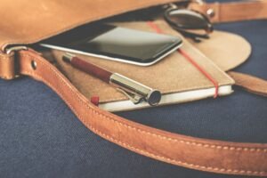 Stylish leather bag with a fountain pen, smartphone, and notebook on display.